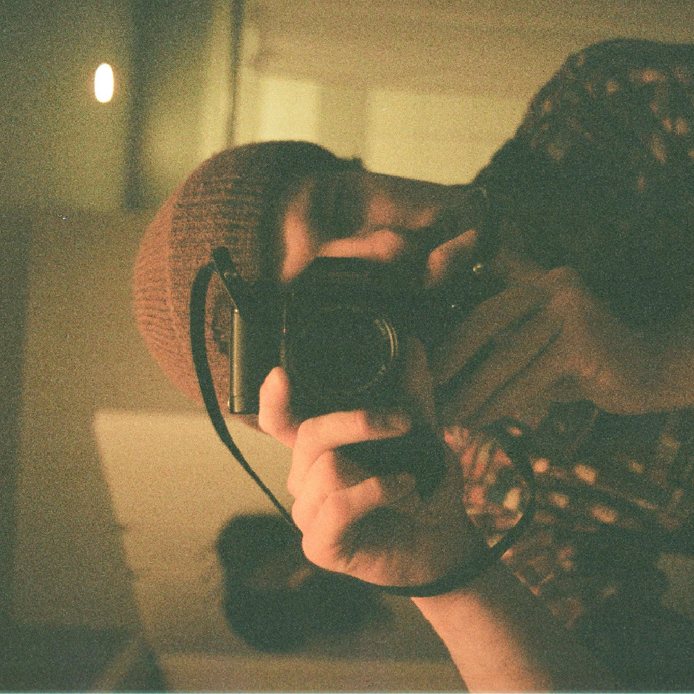 A sideways photo of me taking a picture of the viewer using a 35mm film camera.